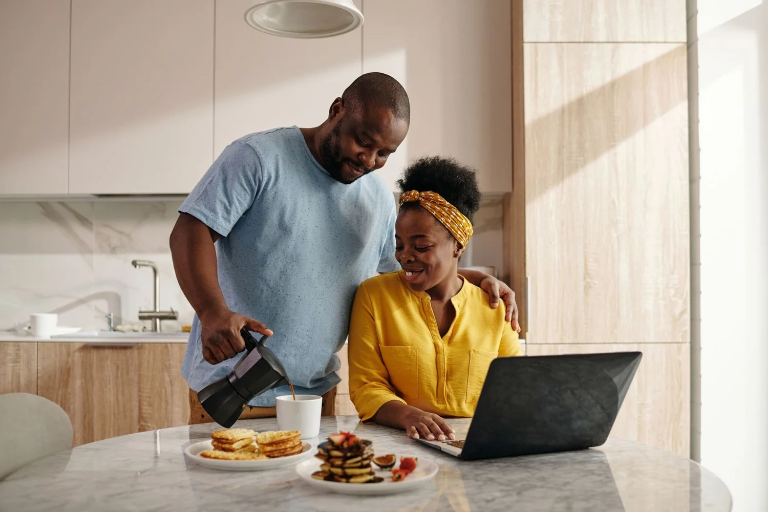 A couple checking rates on a laptop in their kitchen