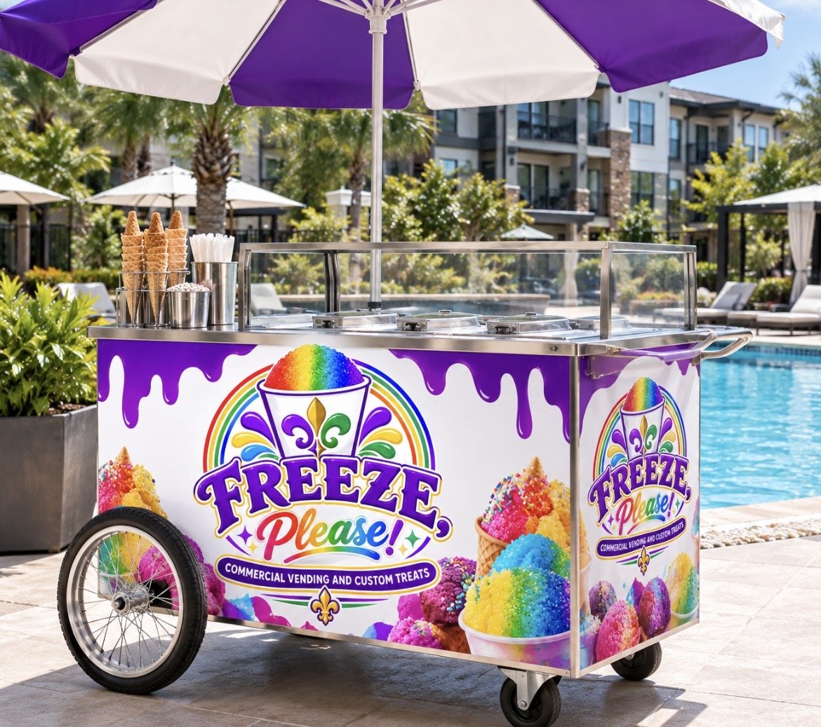 A colorful ice treat cart labeled "Freeze Please!" with slides of rainbow colors and ice treats, positioned next to a swimming pool on a patio with umbrellas, palm trees, and apartment buildings in the background.