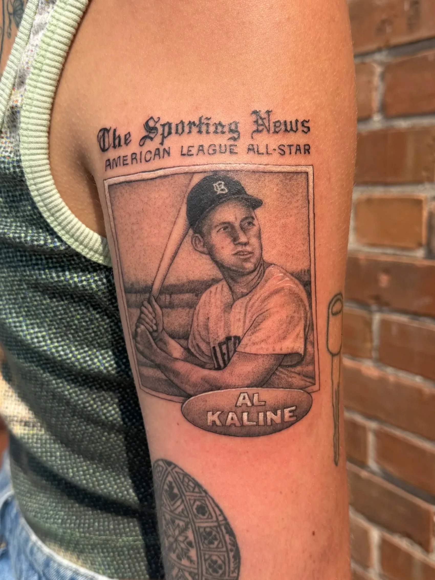 Tattoo of a young baseball player holding a bat at the shoulder, with the text 'The Sporting News American League All-Star' above and 'Al Kaline' below.