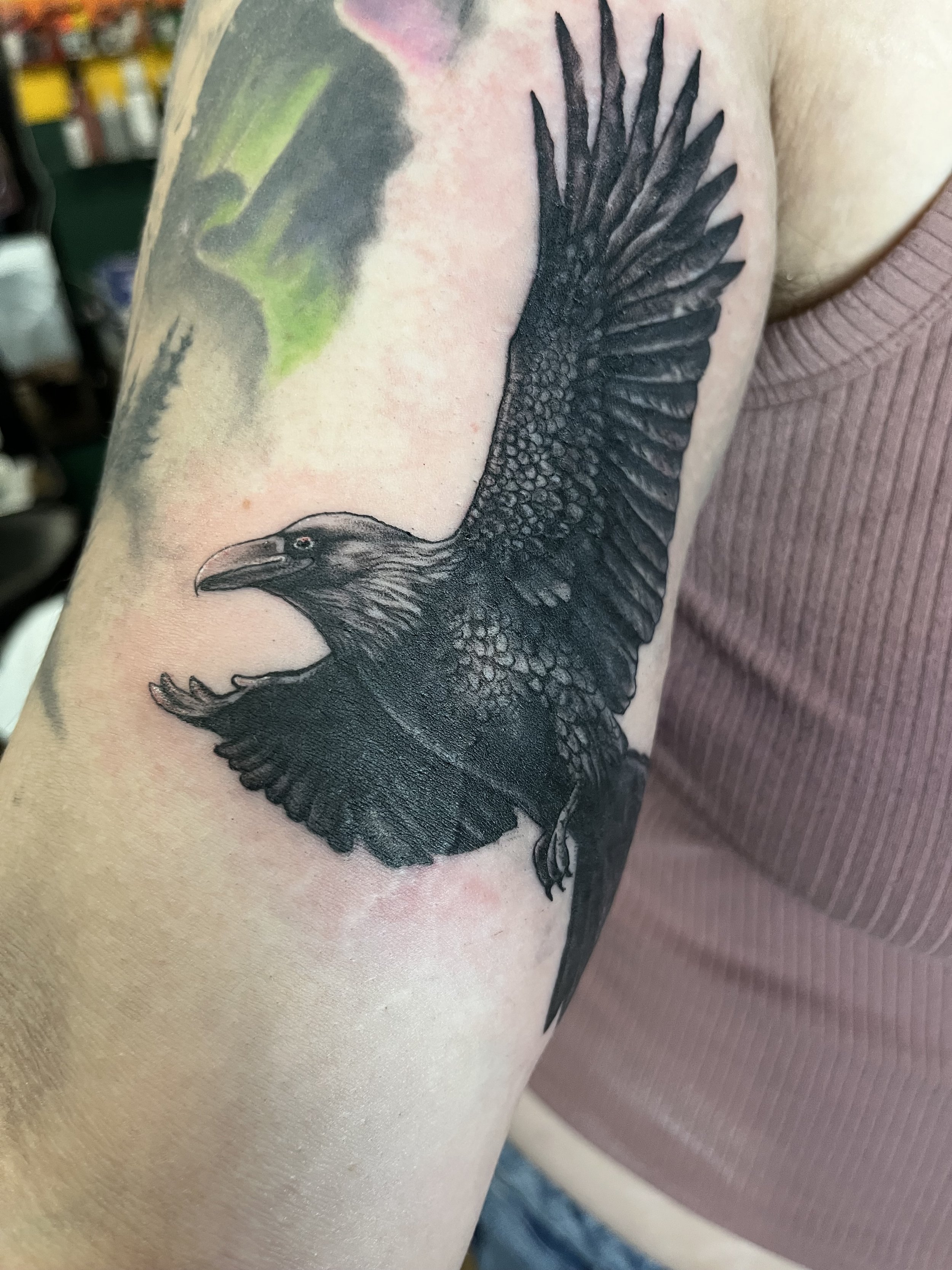 Tattoo of a black eagle in flight on person's upper arm.