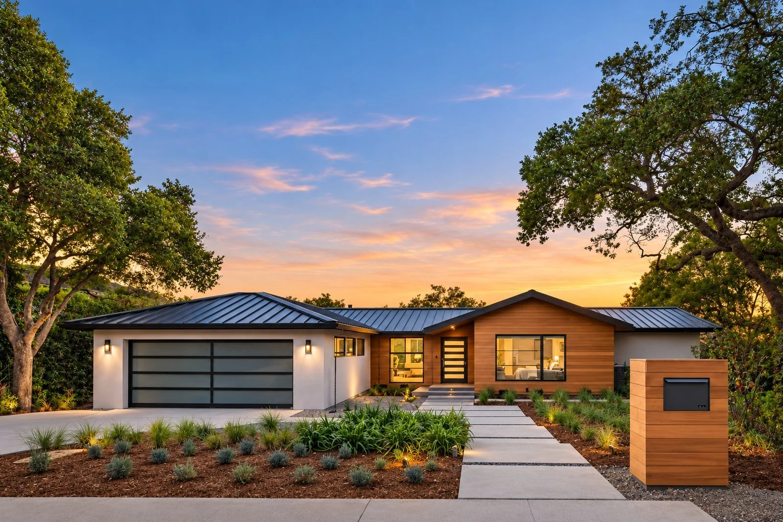 Single-story modern home with wood siding and a dark garage door at sunset