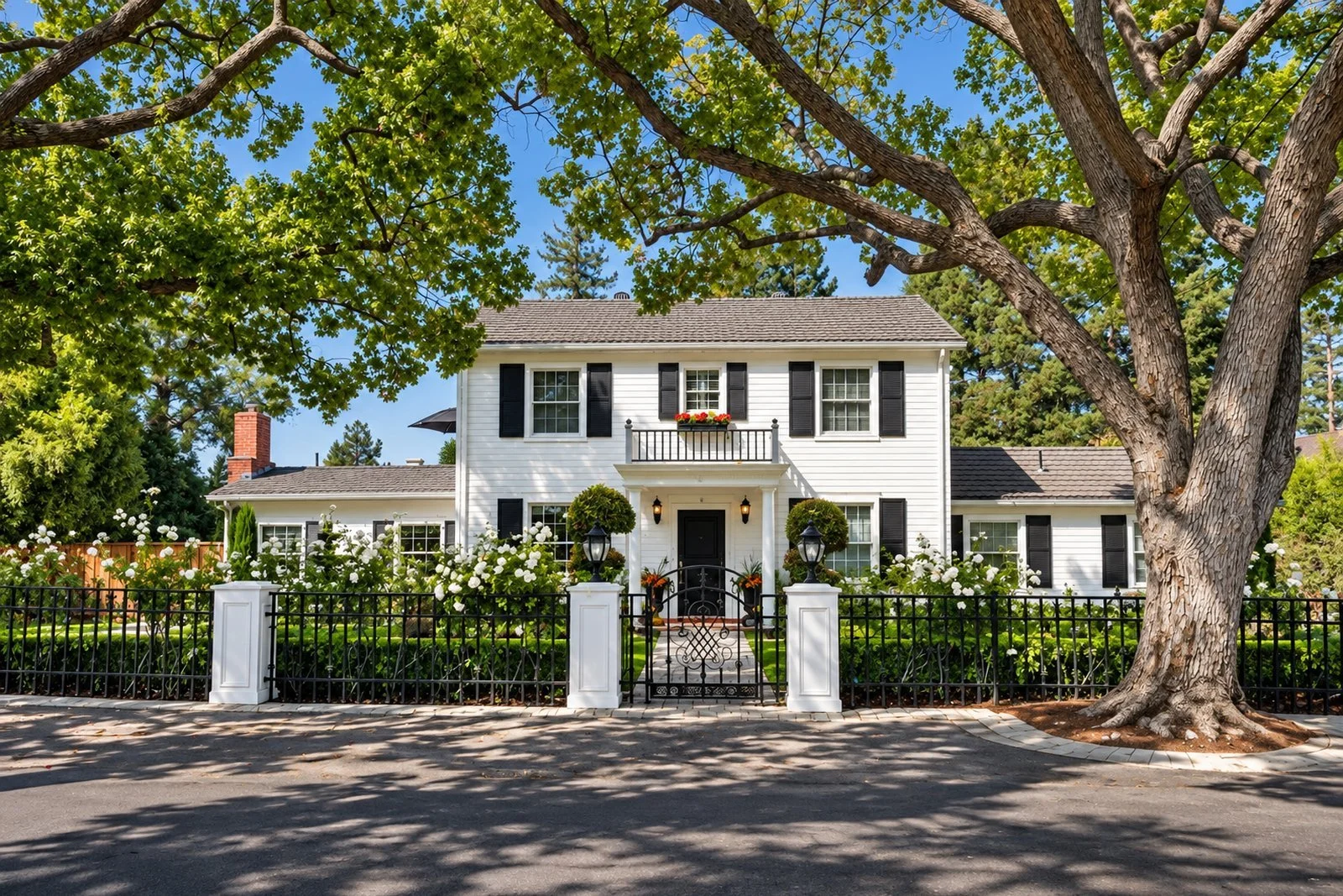 White two-story colonial home with black shutters behind a picket fence