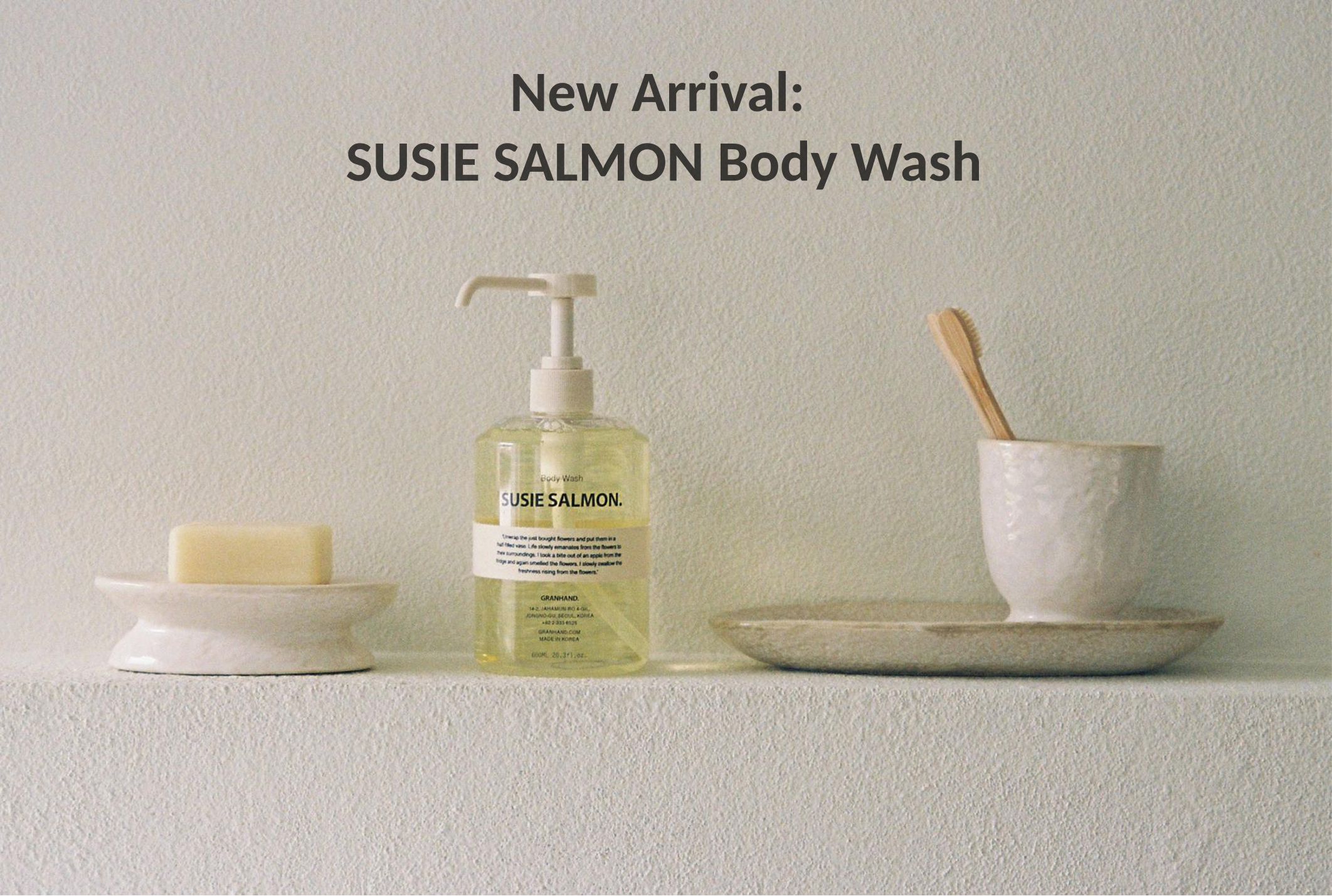 Shelf with Susie Salmon body wash, a soap bar on a dish, and a toothbrush in a ceramic cup with a tray.