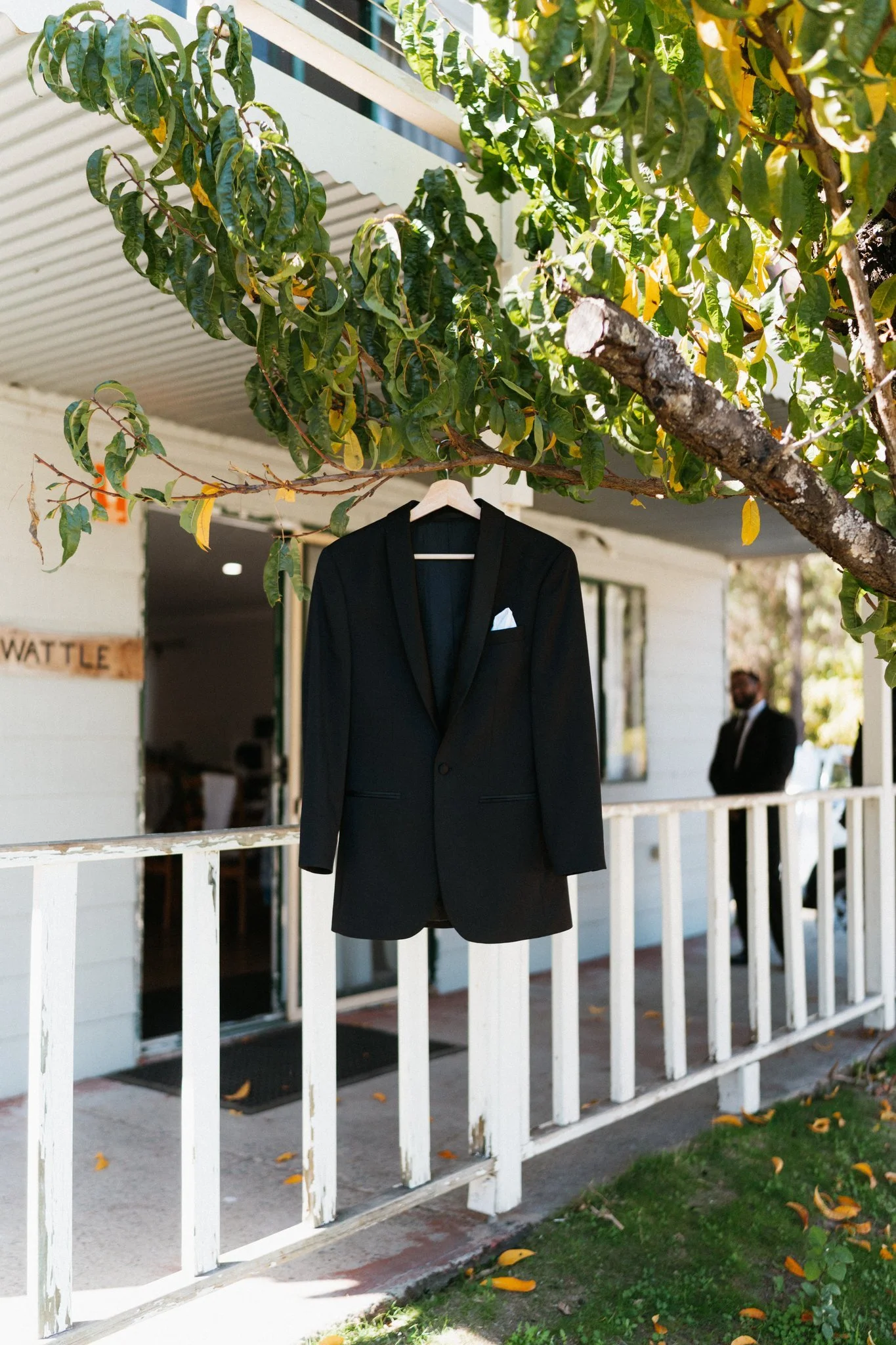 Groom's black suit jacket hanging on a white verandah railing