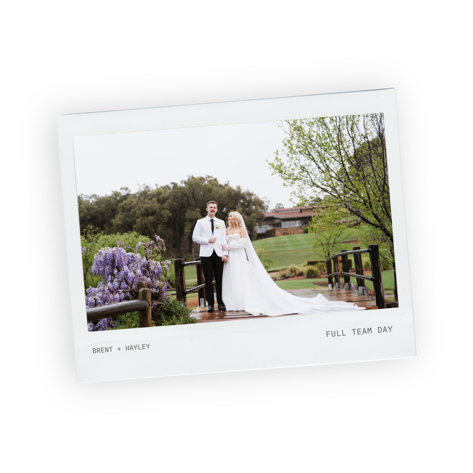 Bride and groom by a garden pond with purple wisteria and green lawns