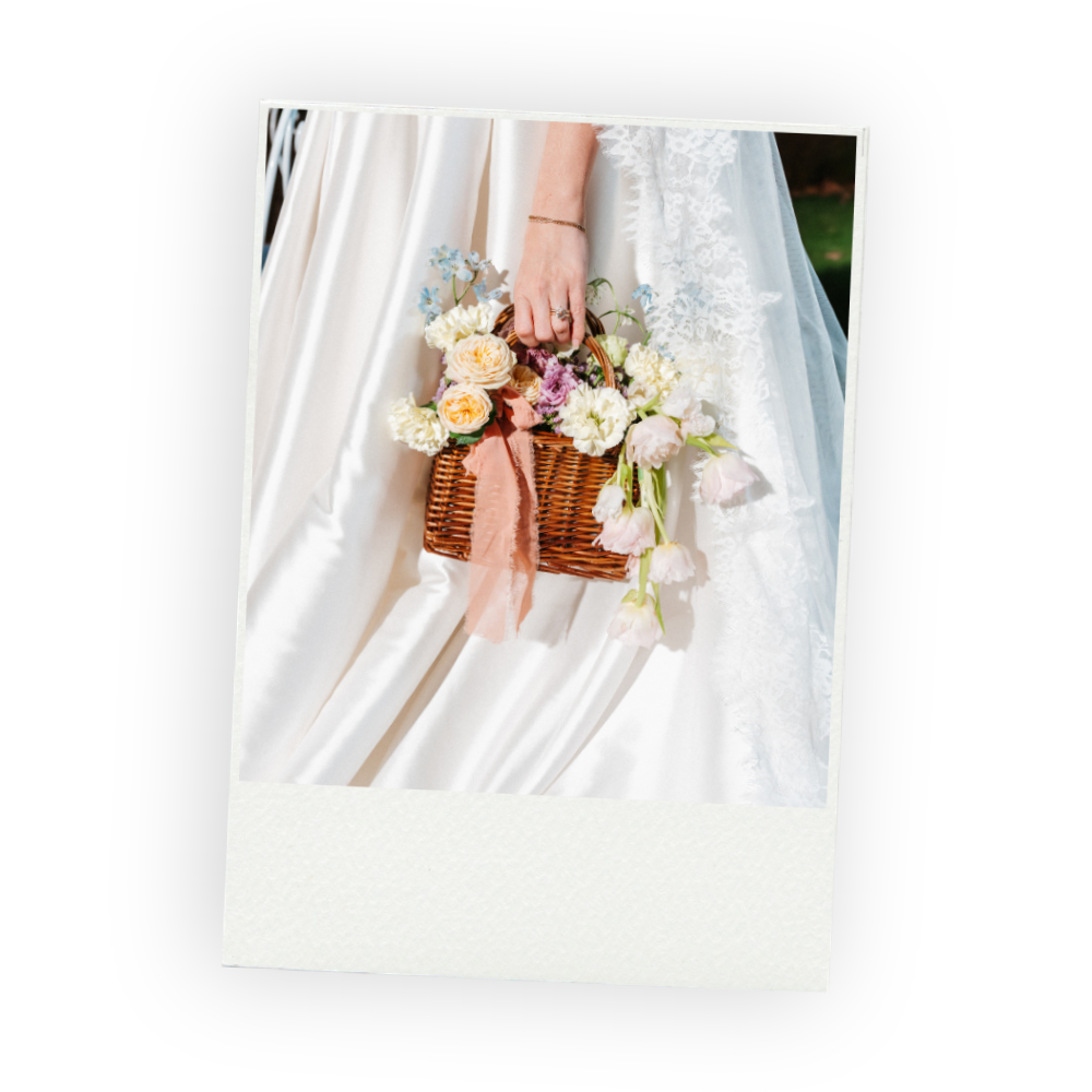 Bride holding a wicker basket of pastel flowers against her white gown