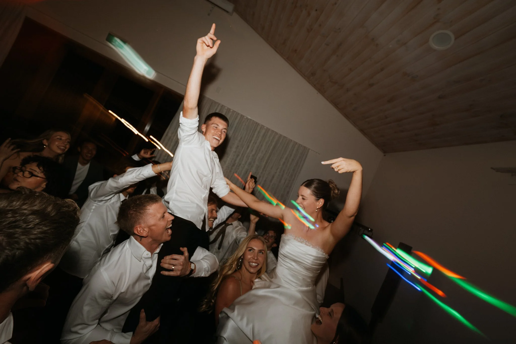 Groom lifted onto shoulders as the bride dances on a busy dance floor