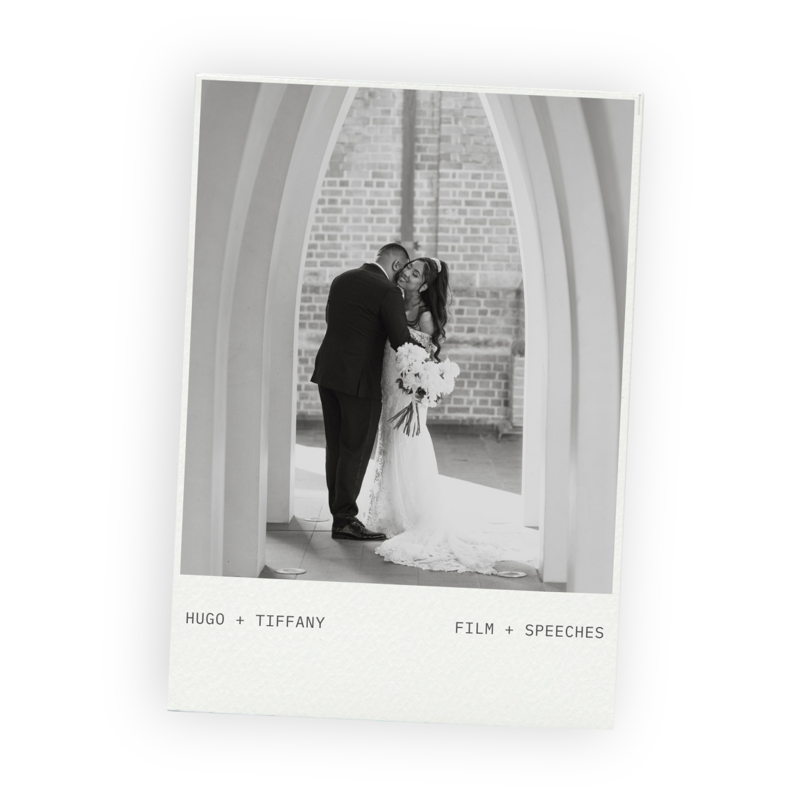 Black and white photo of bride and groom embracing beneath tall white arches