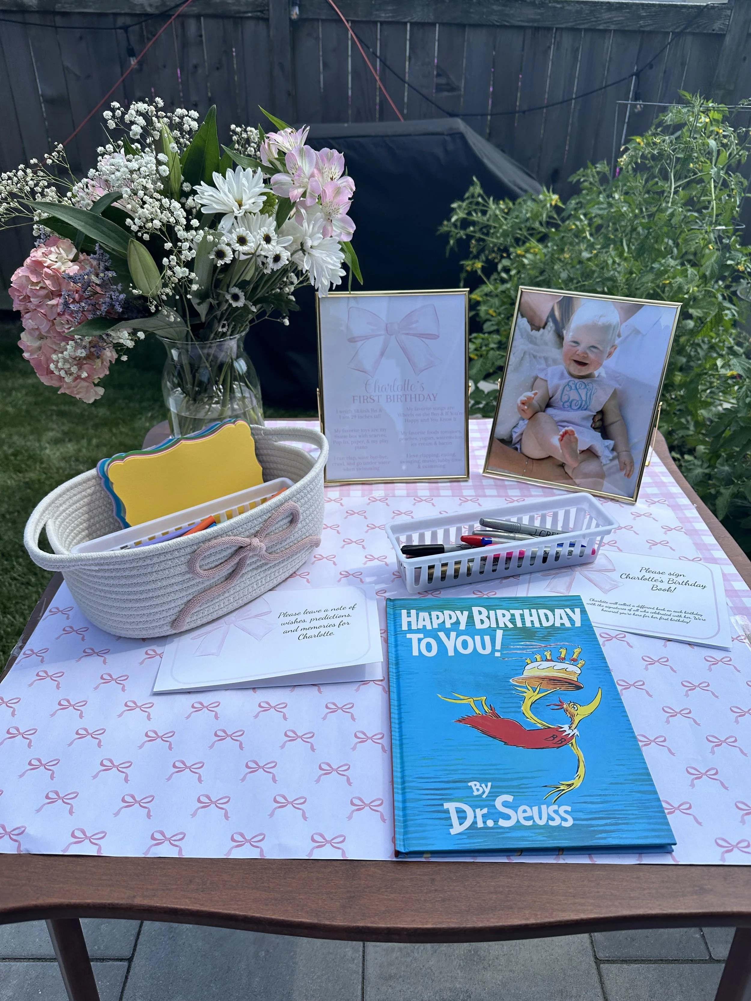Birthday table with flowers, a Dr. Seuss book, photos, and notes for guests to write.