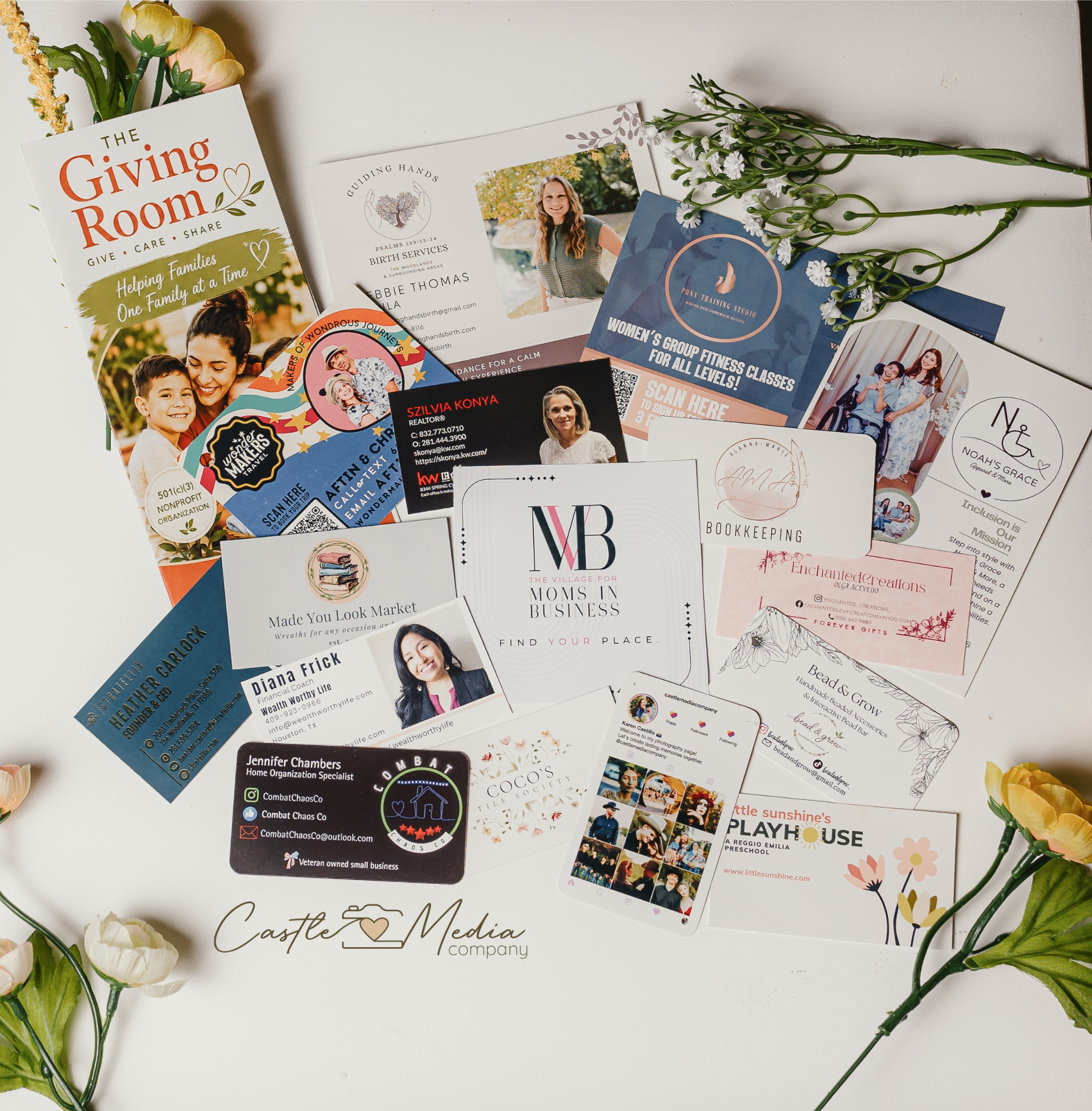 A collection of business and event flyers spread out on a white surface, with some white flowers and yellow flowers on the edges.