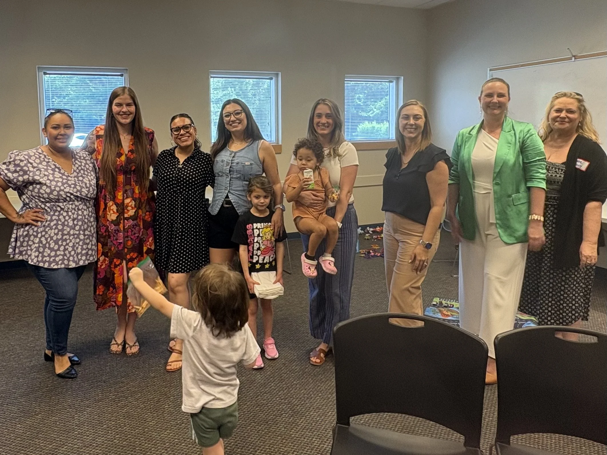 A group of women standing together indoors, smiling for the photo.