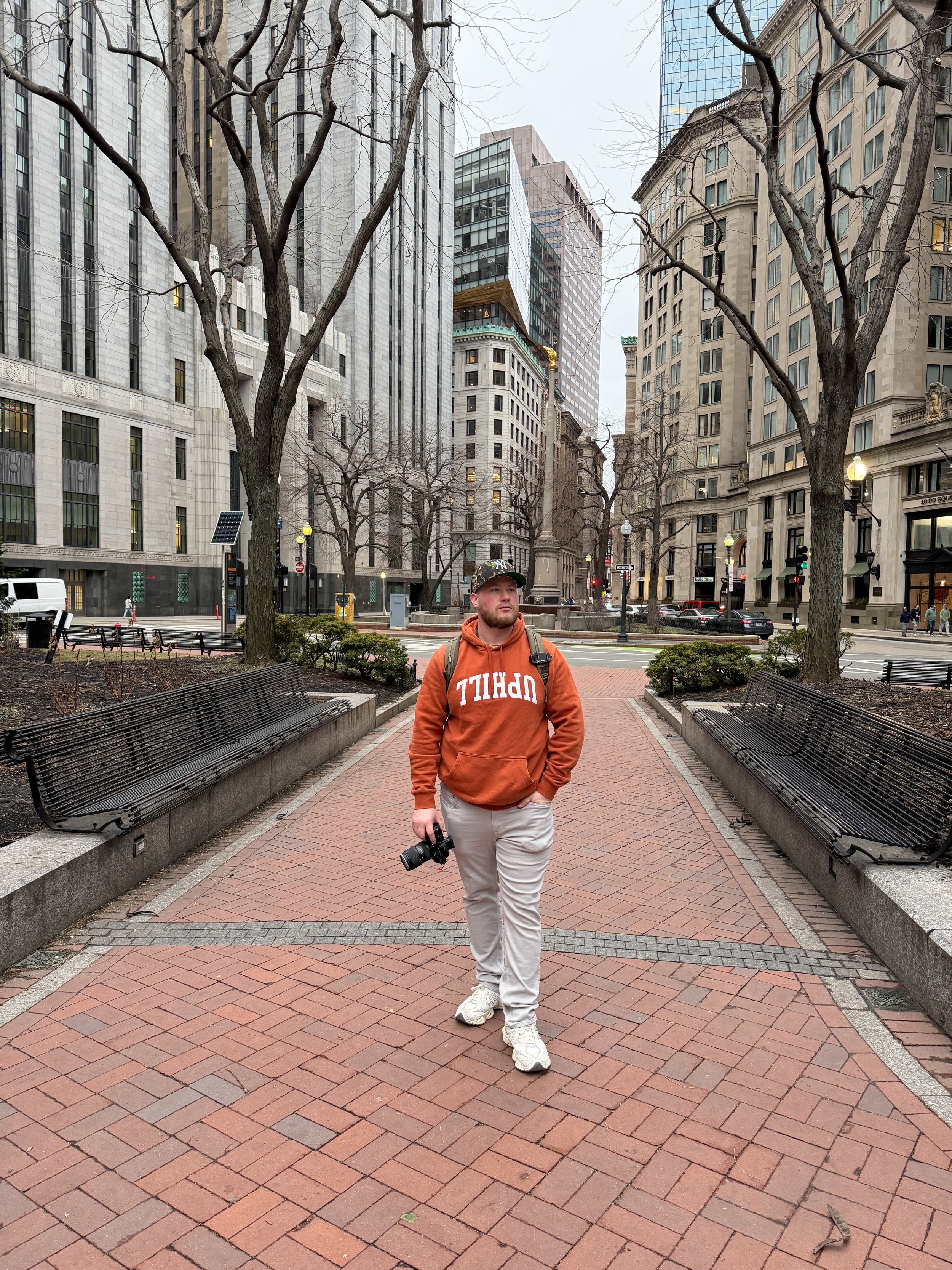Brad wearing a hoodie on a city street downtown Boston, Massachusetts holding his camera