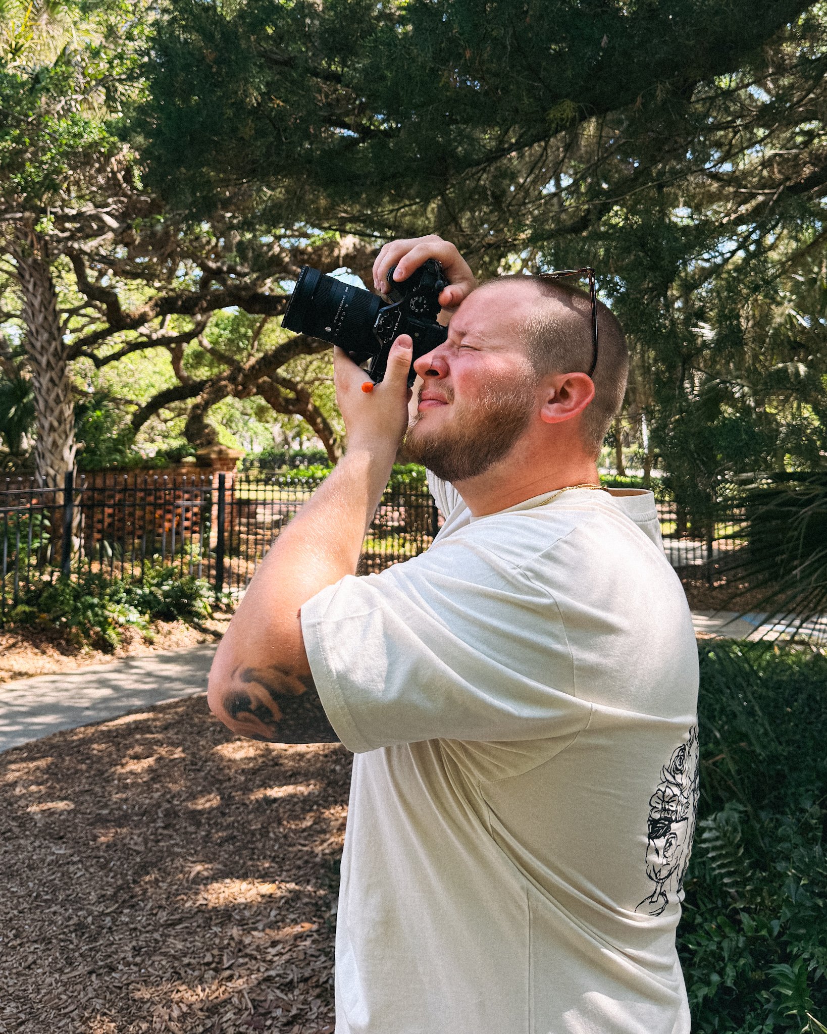 Brad taking a photo outdoors among trees and greenery
