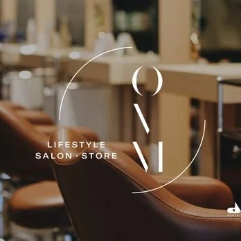 A salon chair in a hair salon with background shelves.