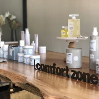 Skincare products displayed on a wooden table with a "comfort zone" sign.