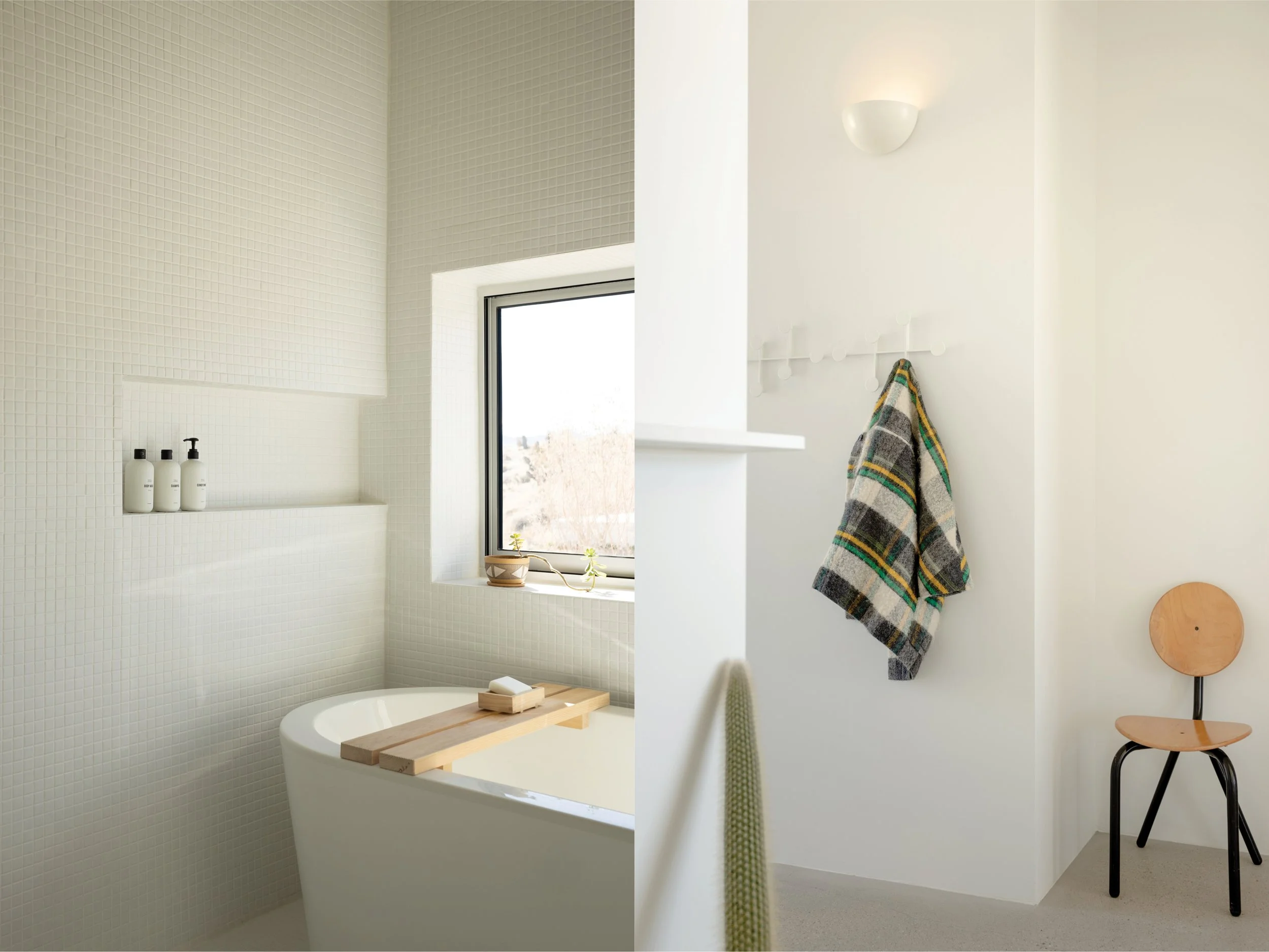 Bathroom details at Panorama House featuring a Neptune Amaze bathtub beside a desert-facing window, Public Goods bath products, a vintage Danish wall lamp, and Audo Copenhagen coat hooks.