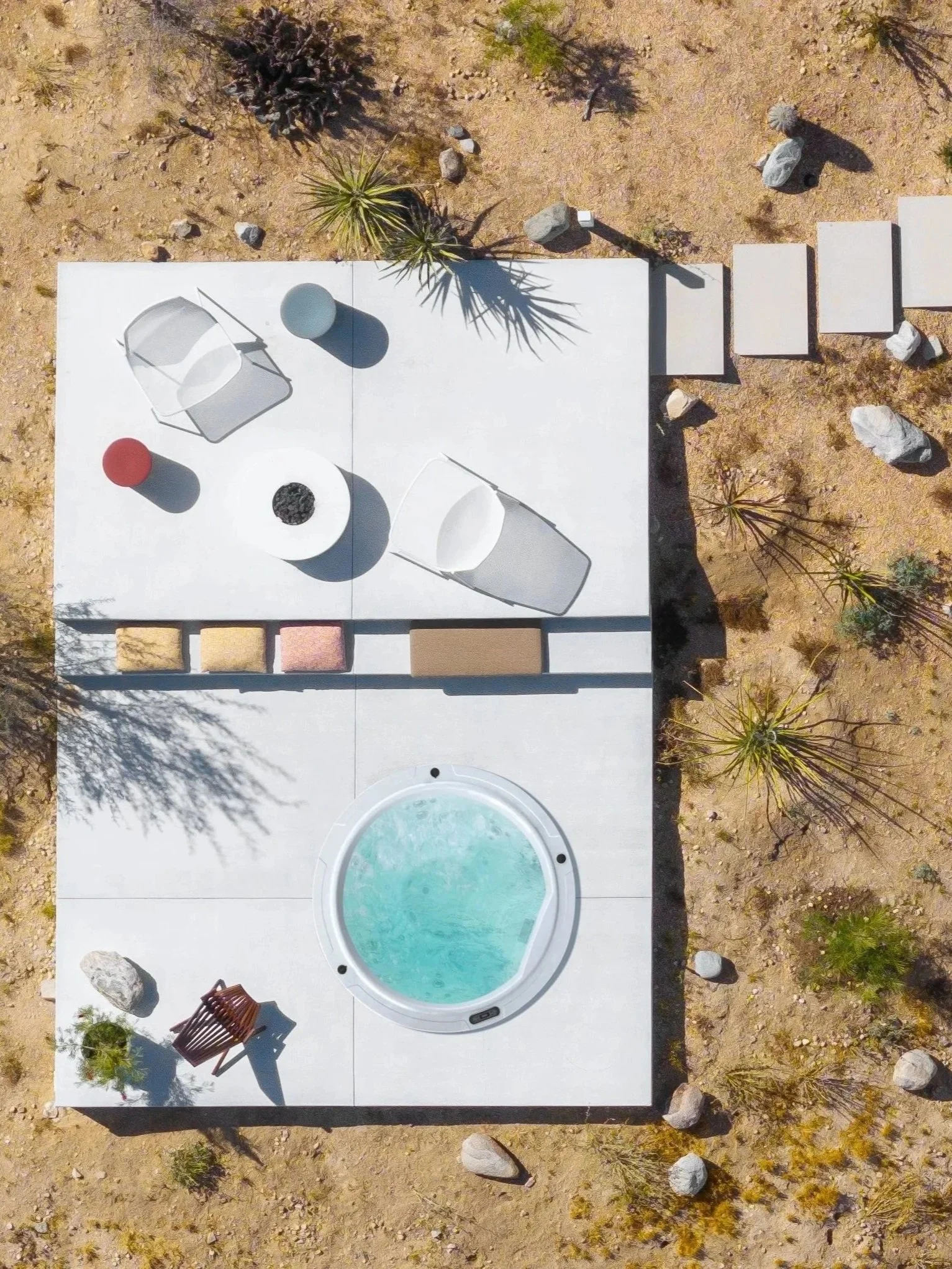 Overhead view of Panorama House's private spa deck in the Mojave Desert, featuring a circular Bullfrog hot tub, Emu lounge chairs, Colosseo side tables by Naoto Fukasawa for B&B Italia, and an Adara fire table.