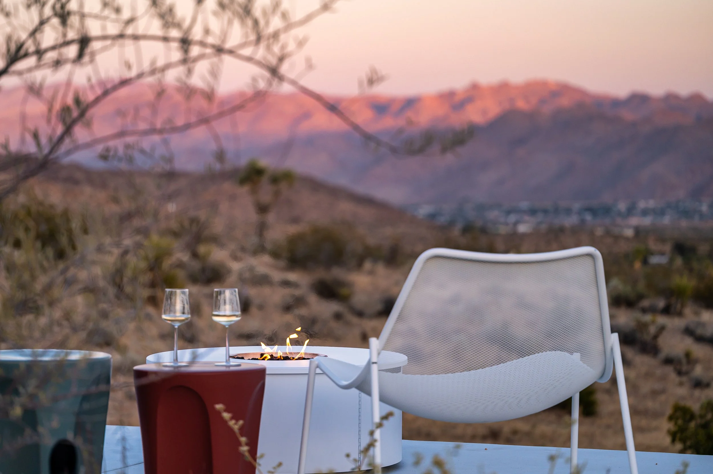 Outdoor lounge at Panorama House overlooking the desert mountains at sunset, with an Emu lounge chair, Colosseo side tables by Naoto Fukasawa for B&B Italia, and an Adara fire table.