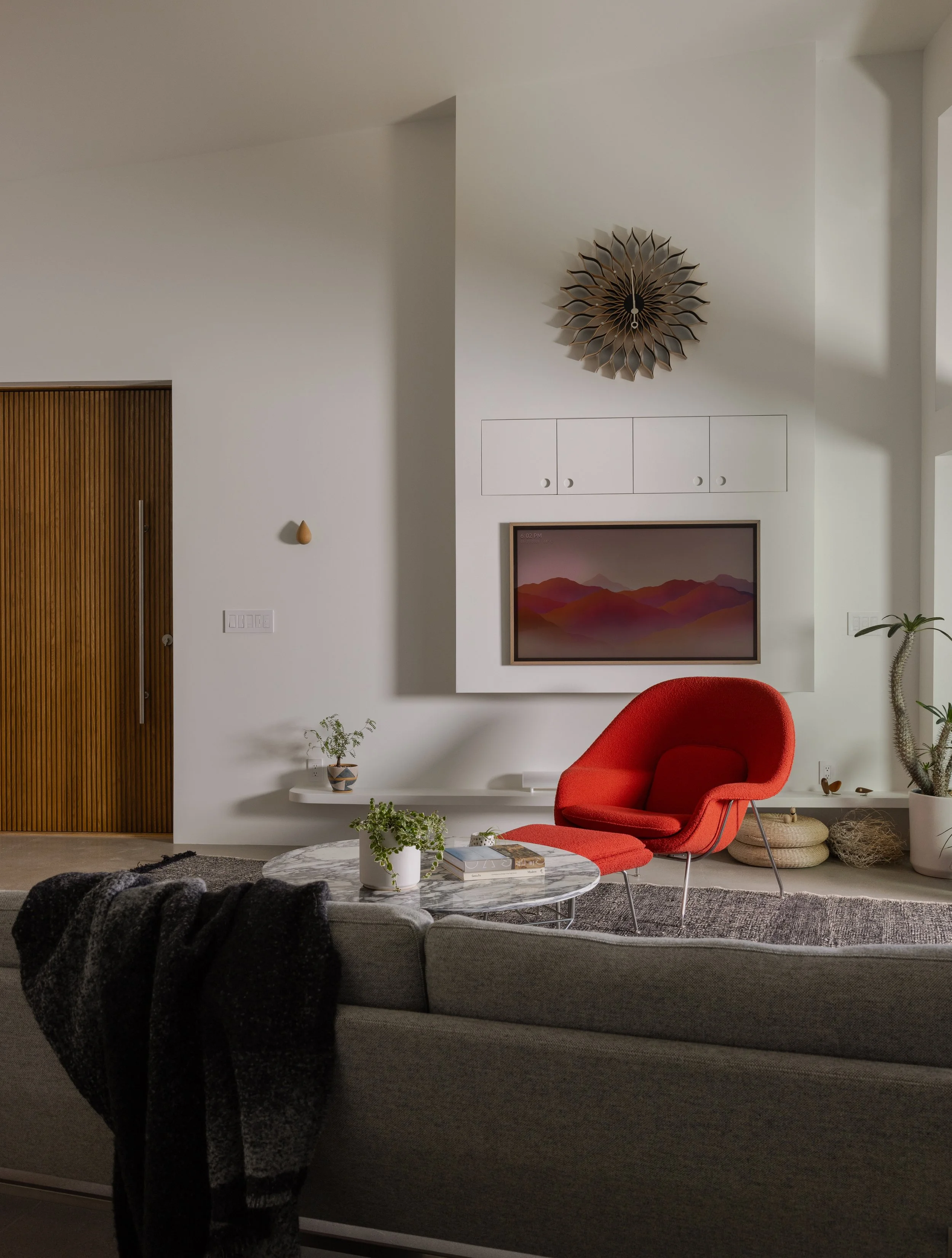 Living room at Panorama House featuring a Knoll Womb Chair, Nelson Sunflower Clock by Vitra, and a sofa designed by Piero Lissoni.