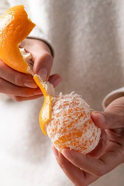 Person peeling an orange to reveal the inside of the fruit.