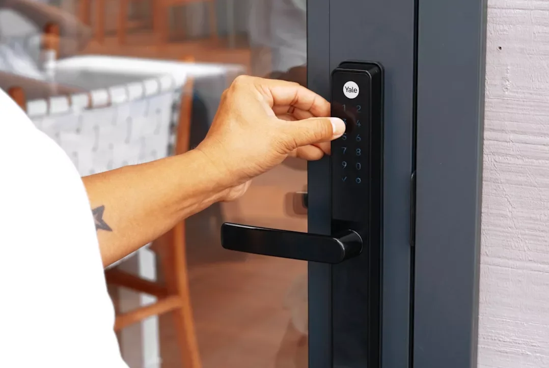Person using a Yale digital keypad lock on a door.
