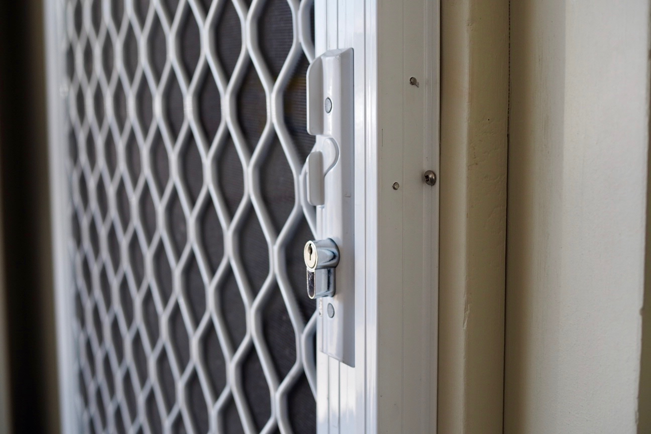 Close-up of a door lock and security grille, likely at an entrance or exit.