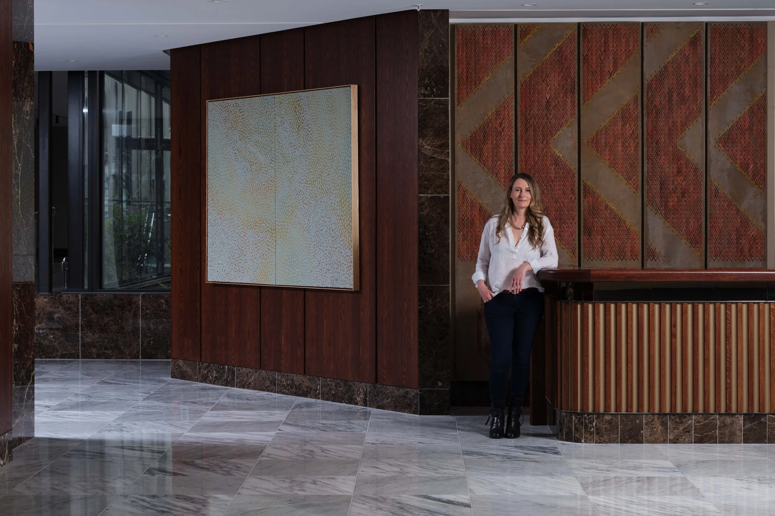 Sophie Coupland standing in the Cordis hotel lobby showcasing artwork she soured for this large hotel public project.