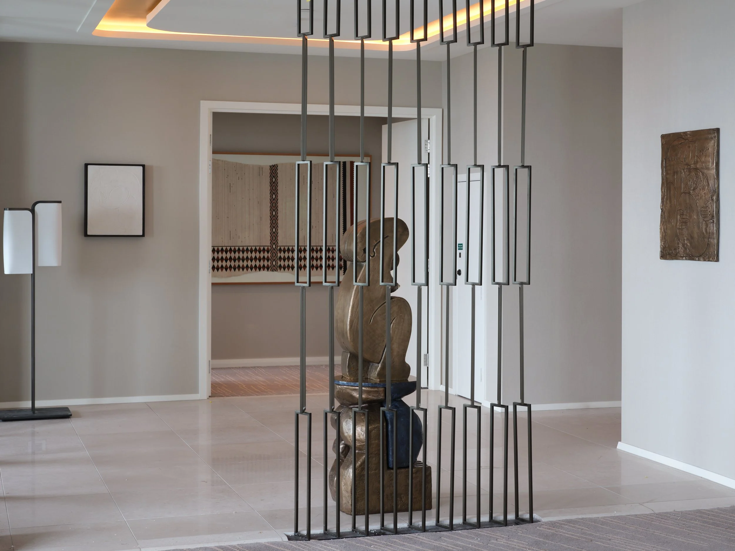 Sanne Mestrom bronze sculpture behind a metal wall divider in public area at Cordis