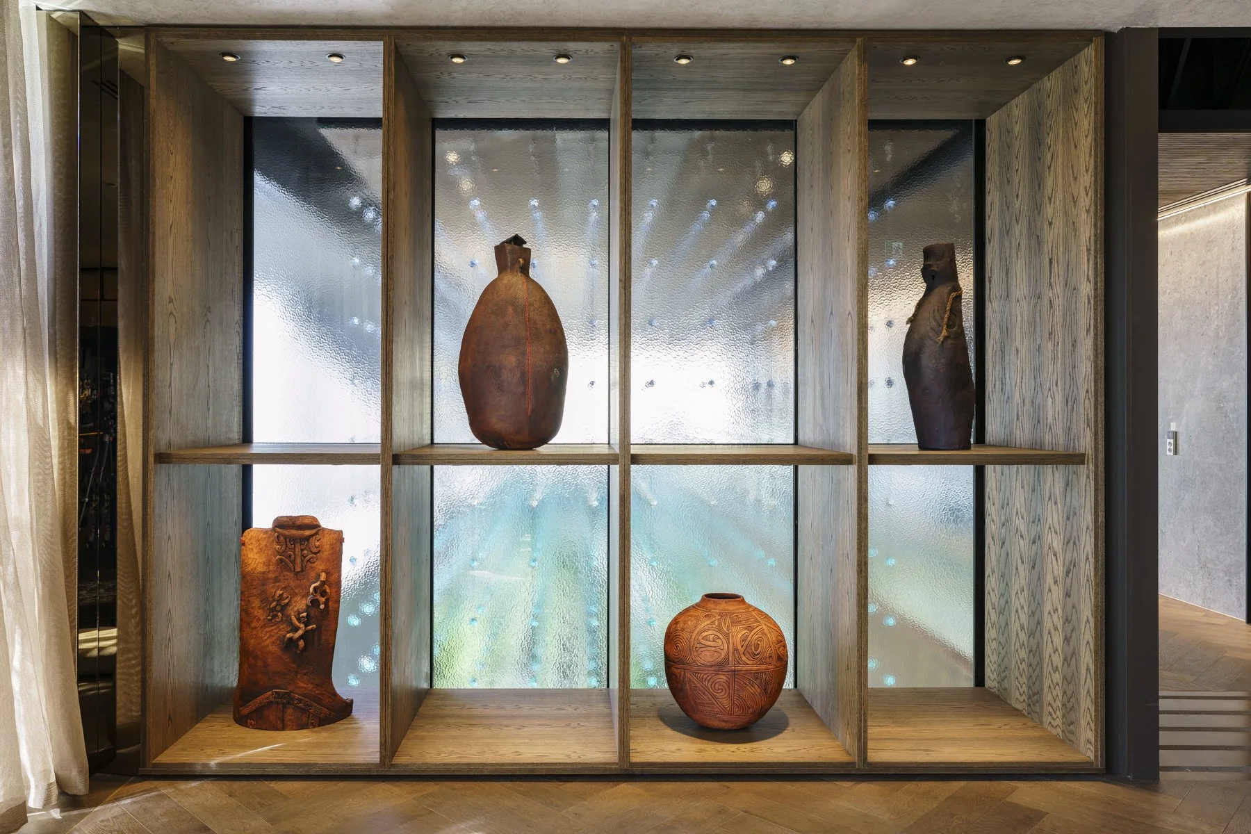 Four Wi Taepa carved clay works on a multi-square wooden shelf