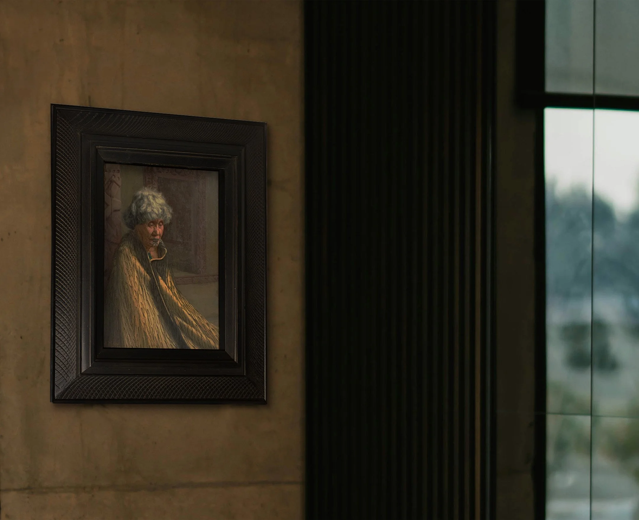 A framed Goldie portrait hanging on a wall, with a window visible on the right side.