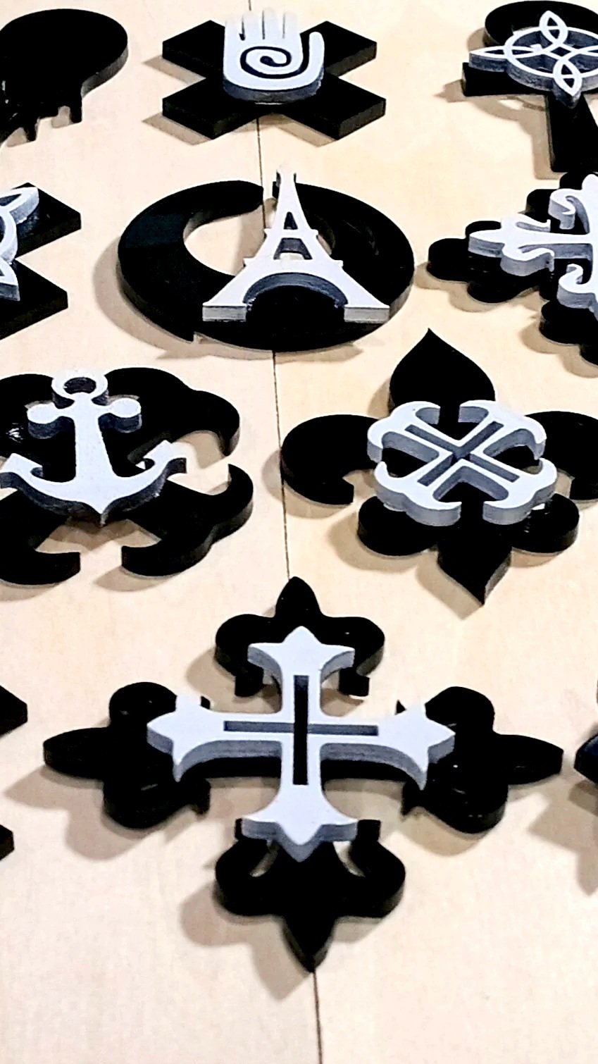 Chess pieces shaped like snowflakes, symbols, and shapes, arranged on a light-colored surface.