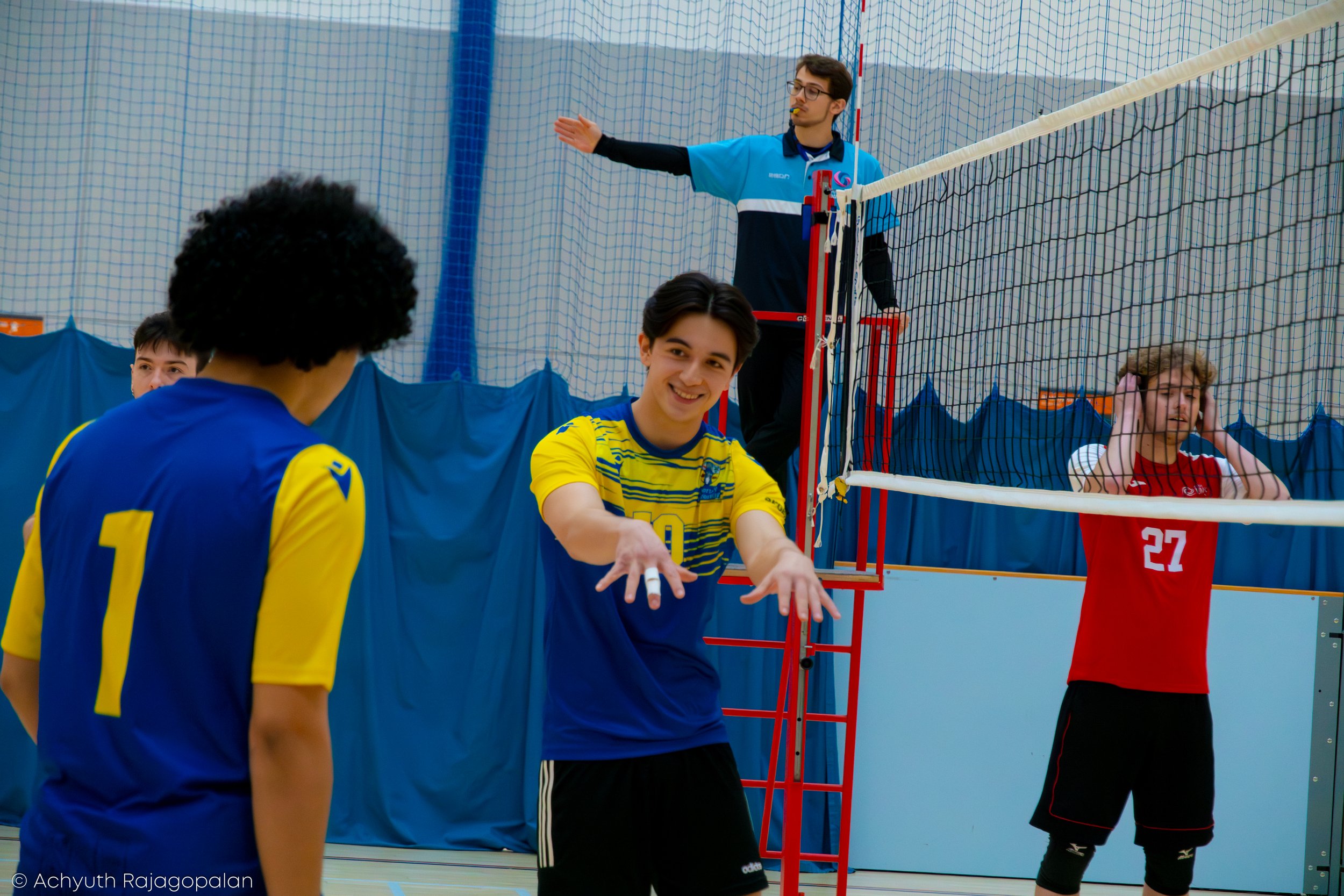 Indoor volleyball practice session with players and referee