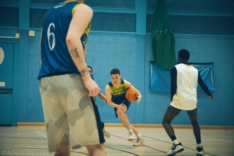Young basketball players practicing dribbling drills on an indoor court.