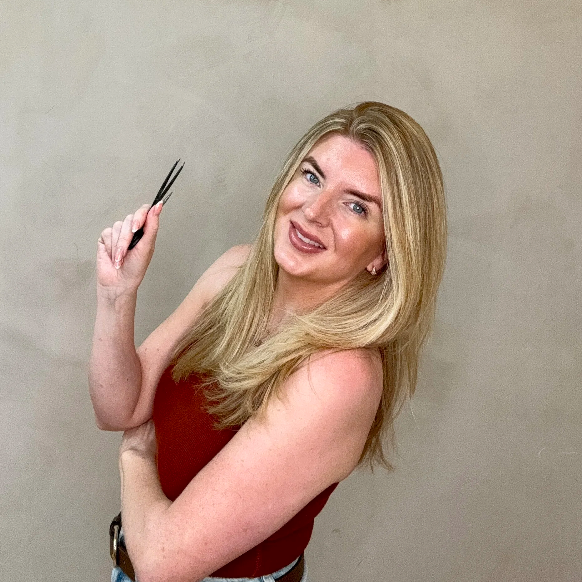 Emma Rose smiling and holding brow tweezers.