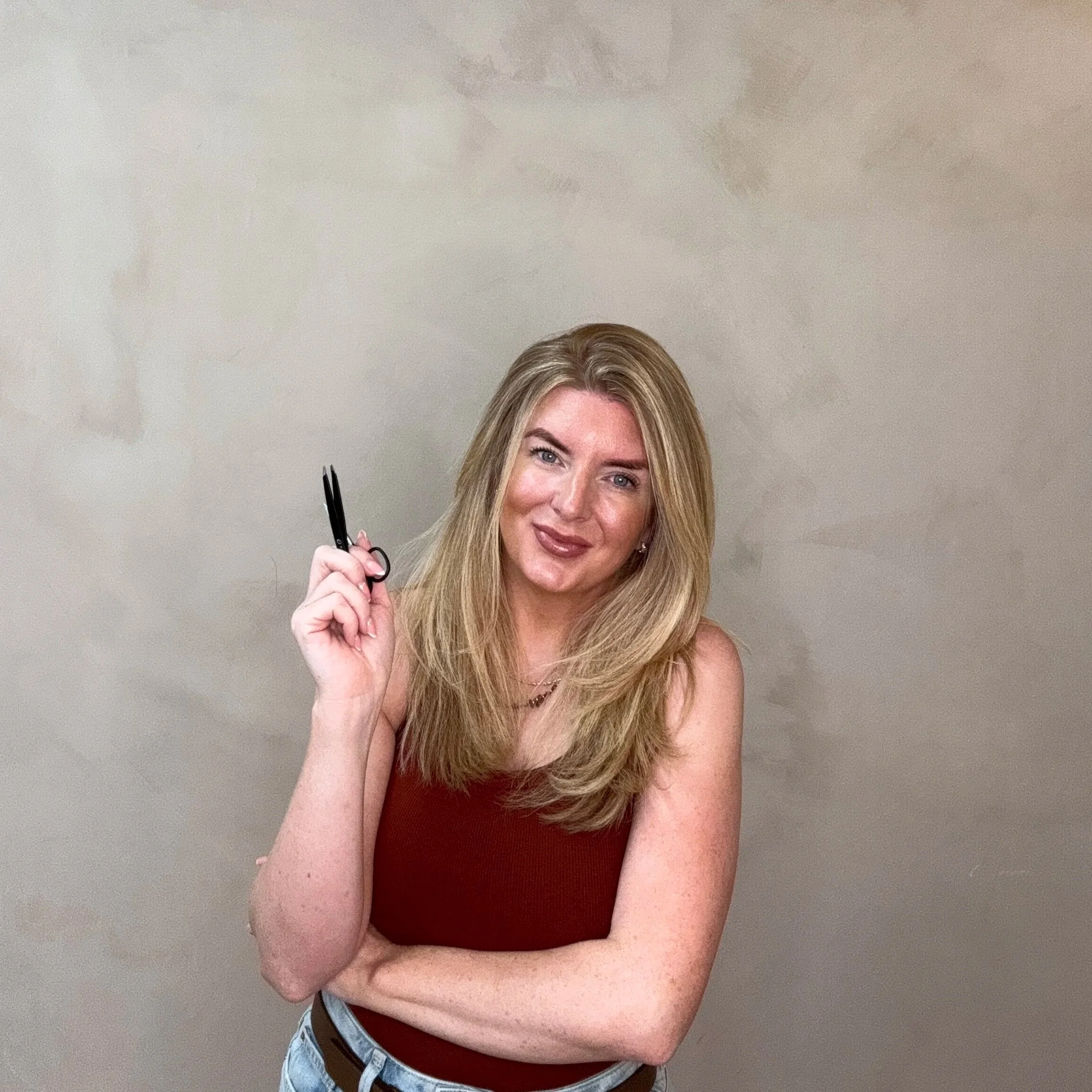 Emma Rose posing in a burgundy sleeveless top against a neutral wall.