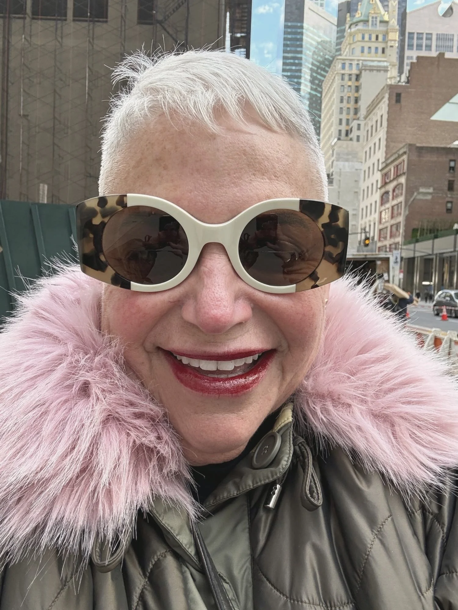 Eve Ruff smiling on a New York City street in a pink faux fur collar