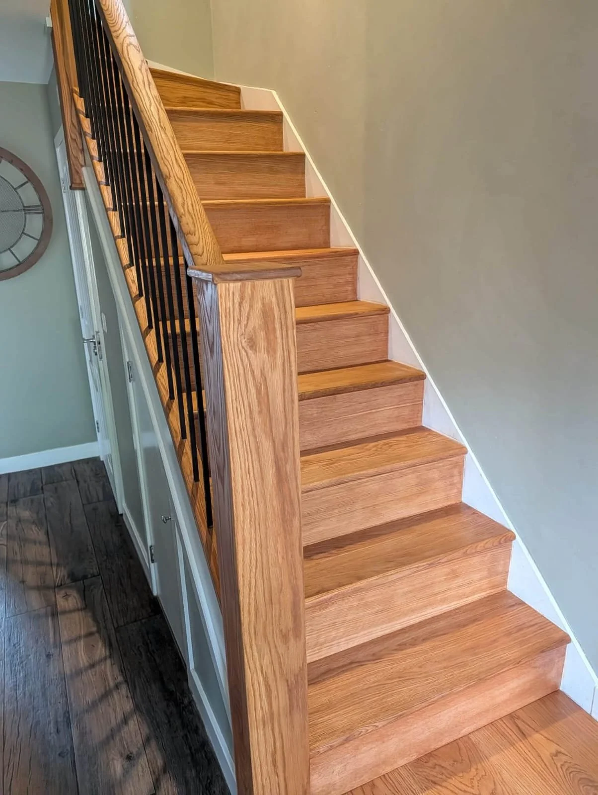 Oak staircase with black metal balusters and wooden handrail in a residential interior