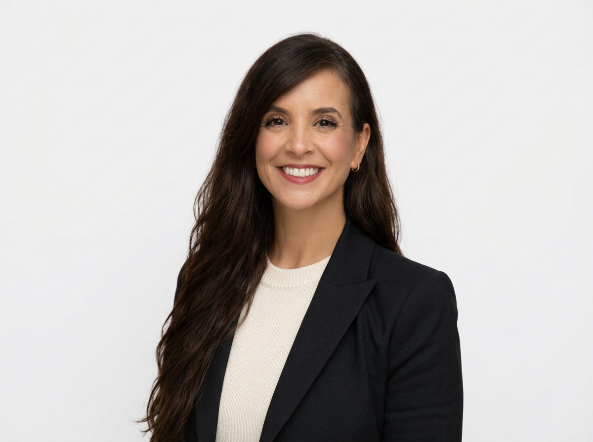 Professional portrait of a woman with long dark hair smiling, wearing a black blazer and a white top, against a plain white background.