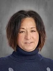 Woman with shoulder-length dark hair wearing a blue turtleneck sweater, smiling, against a gray background.