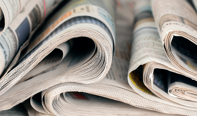 Close-up of newspapers rolled and layered on a surface.