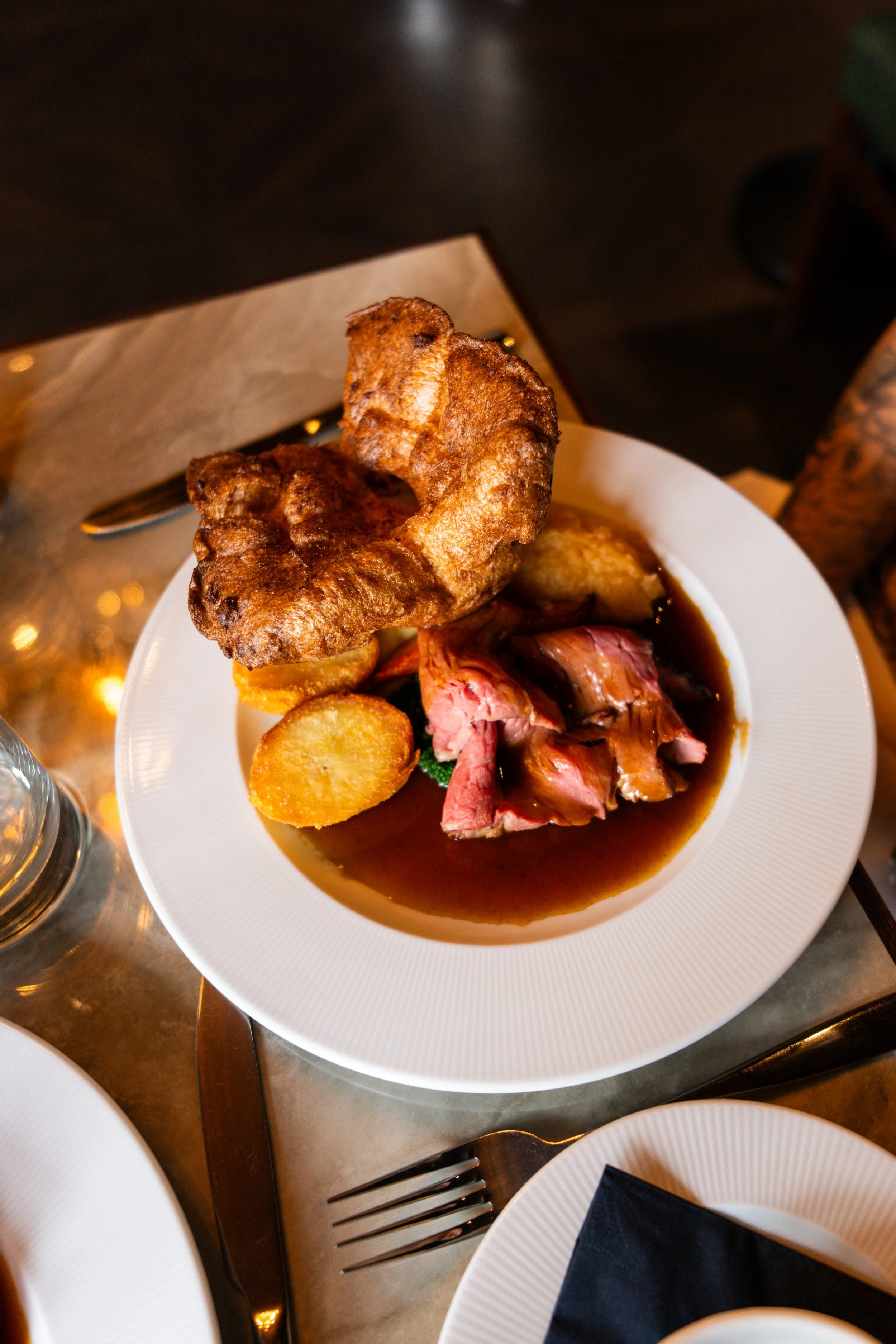 A plate of roast beef with gravy, roasted potatoes, and Yorkshire pudding.