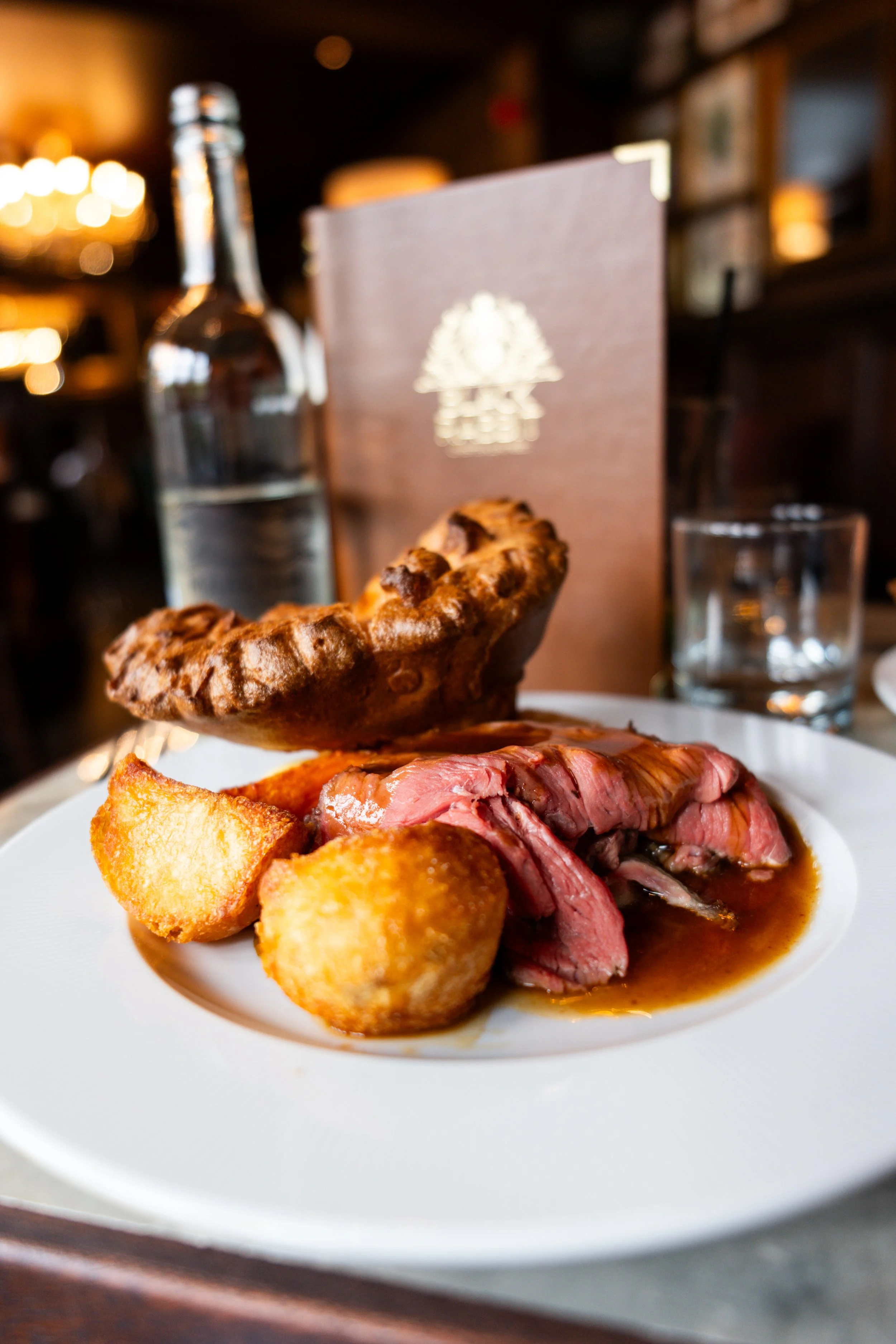 A plate of prime rib with horseradish potato croquettes and Yorkshire pudding in a fine dining restaurant setting.