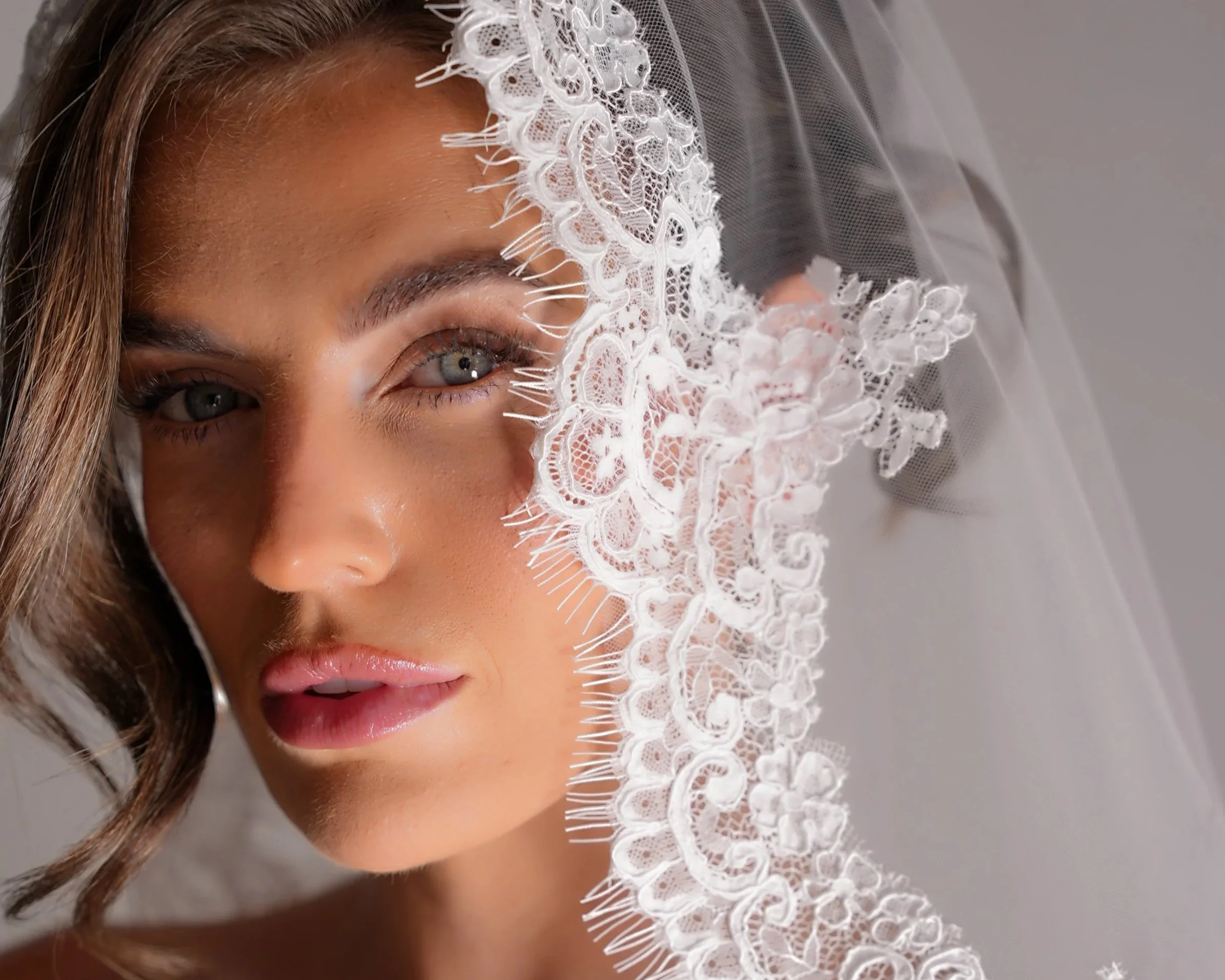 A close up portrait by Willow Victoria Photography of a beautiful bride with her bridal hair and make up with a lace mantilla veil