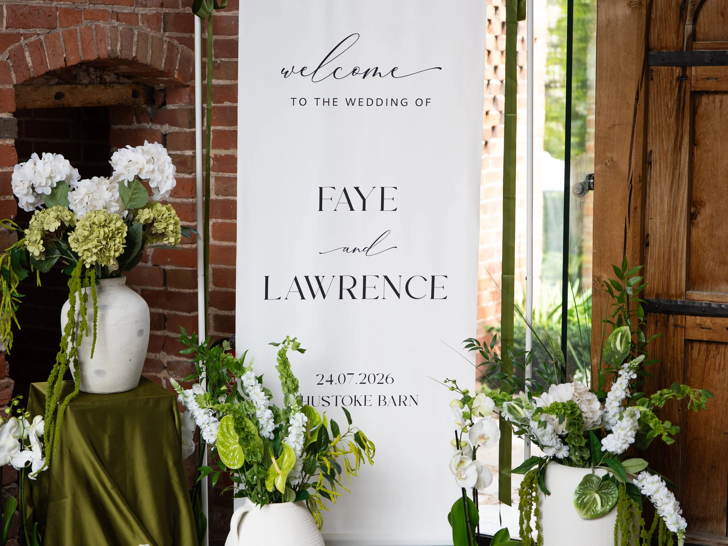 Wedding welcome sign with floral arrangements at Shustoke Barn.