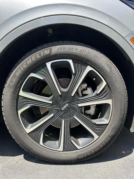 Close-up of a car tire and alloy wheel on a silver vehicle, showing the tire brand Michelin and size 255/50 R 21.