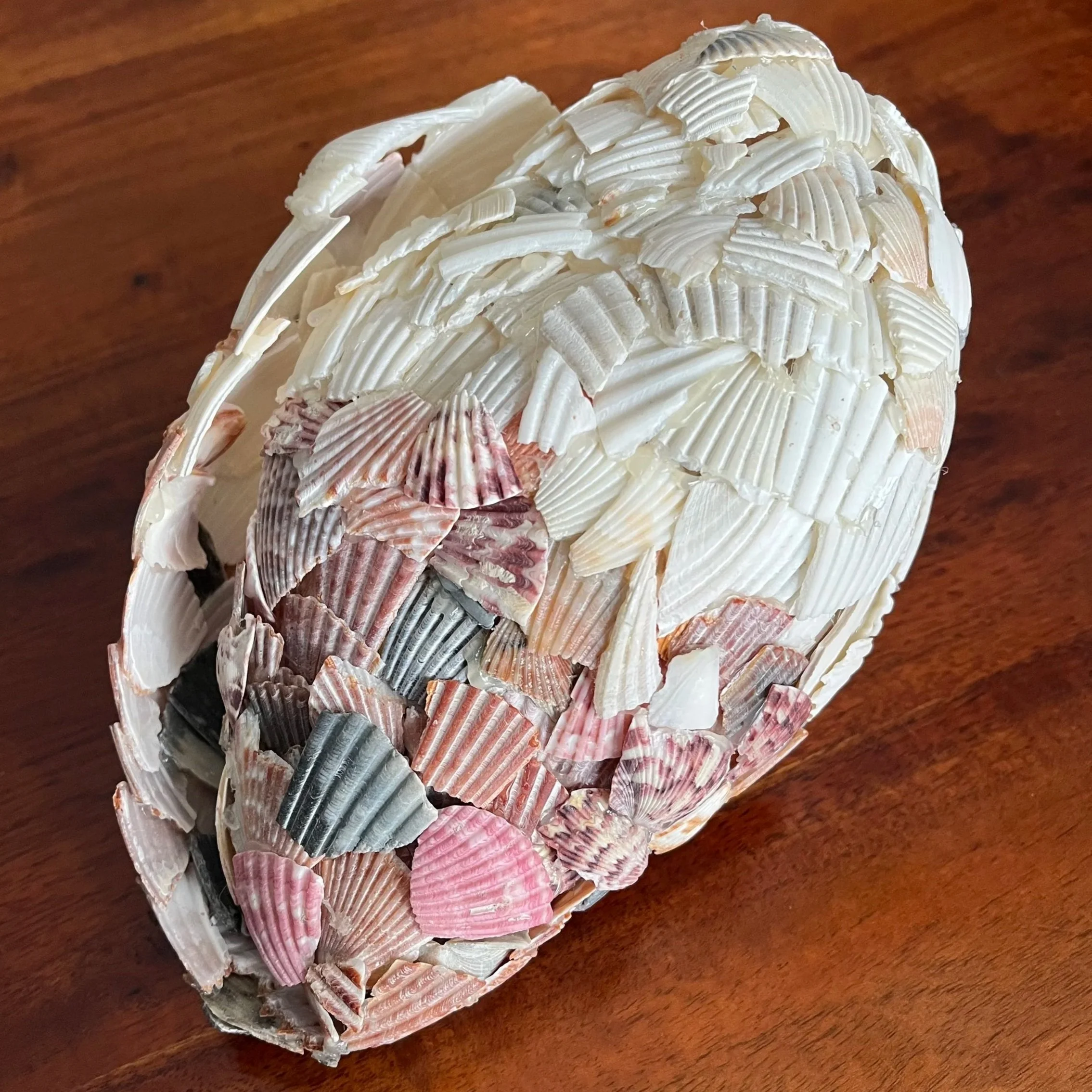 Close-up of a seashell shell art sculpture on a wooden surface.