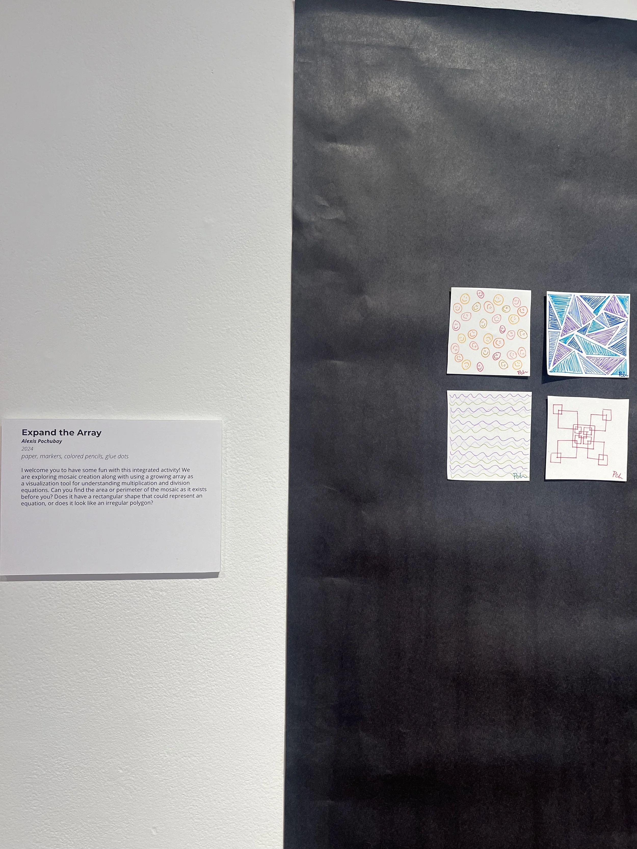 A display of four abstract drawings on paper, mounted on a black background. The top left features multicolored smiley faces, the top right showcases a geometric pattern with blue and purple triangles, the bottom left contains a pattern of purple squ