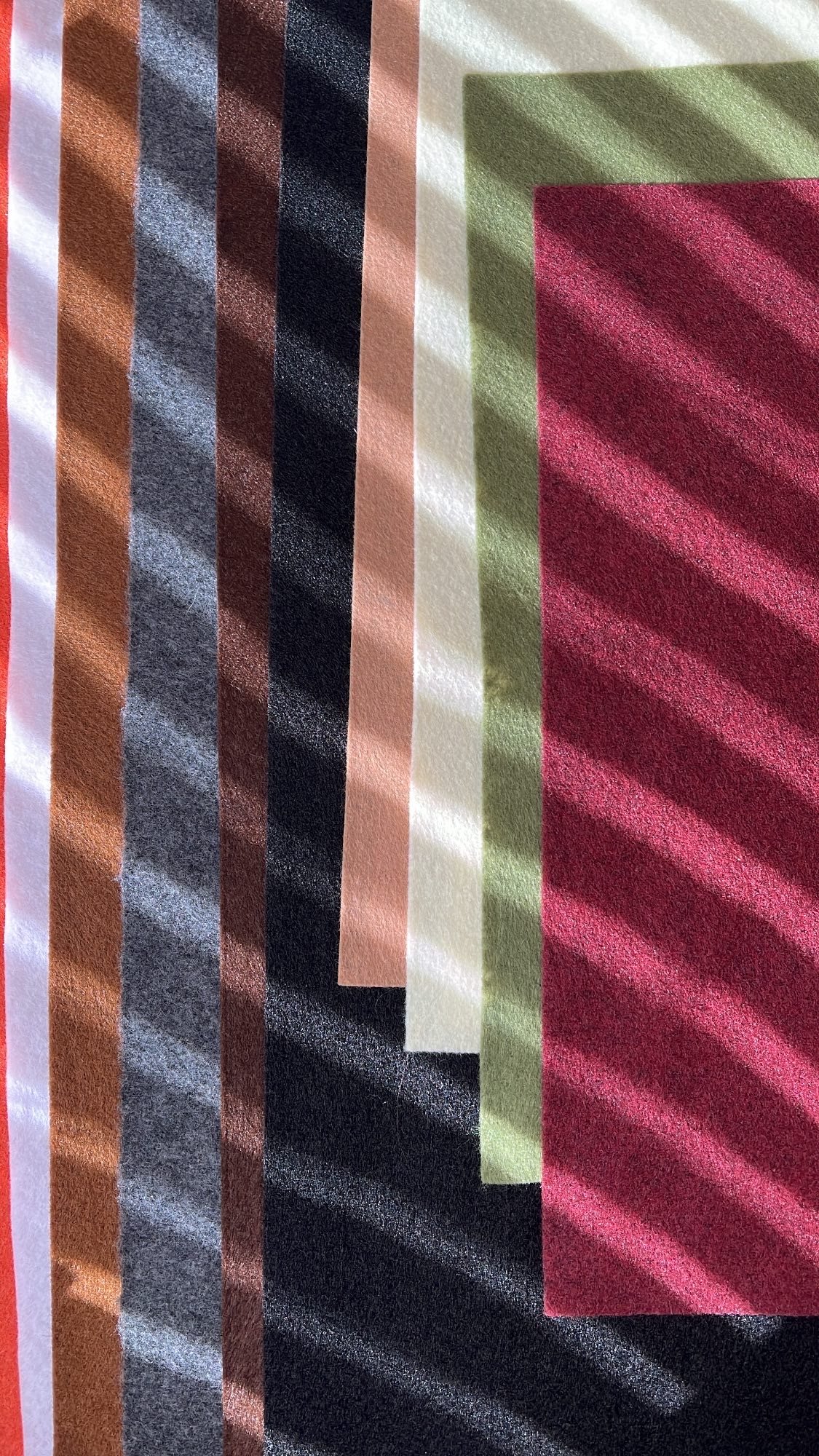 Close-up of a colorful striped textile with shades of pink, red, green, black, white, orange, and purple.