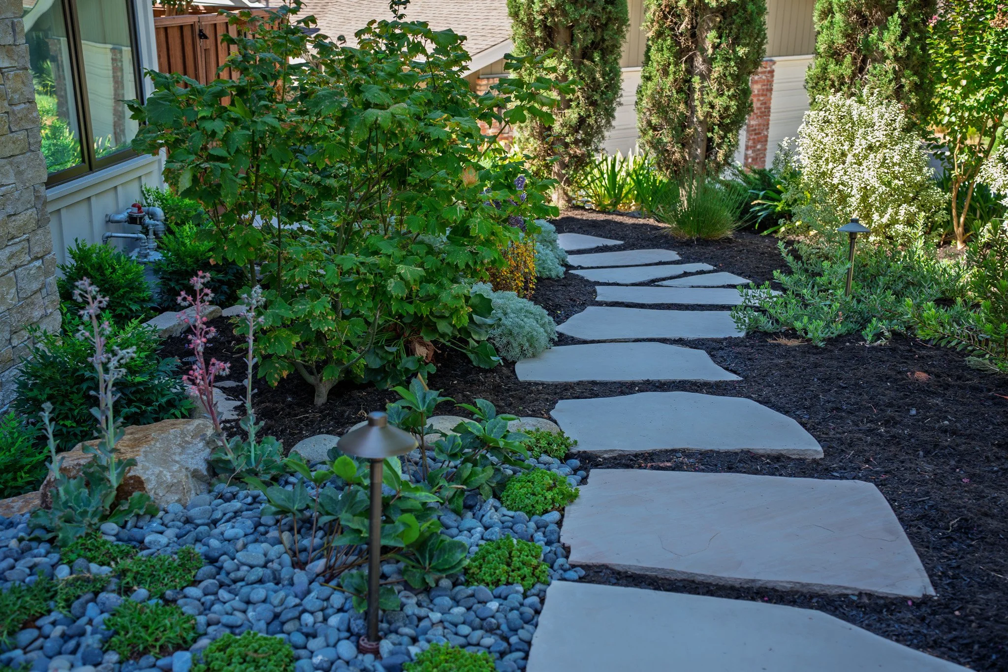Flagstone stepping-stone path with landscape lighting and river rock beds, hardscaping by G&H Landscaping