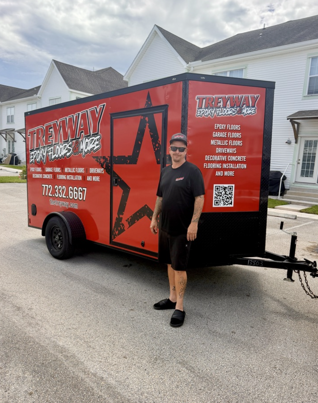 A man standing in front of a red mobile trailer for Trewyay Epoxy Floors & More, parked on a residential street.